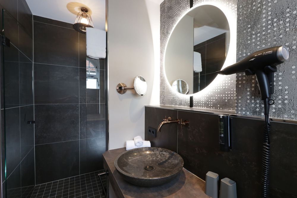 Das stilsichere Badezimmer mit ebenerdiger Regendusche und Steinbecken.