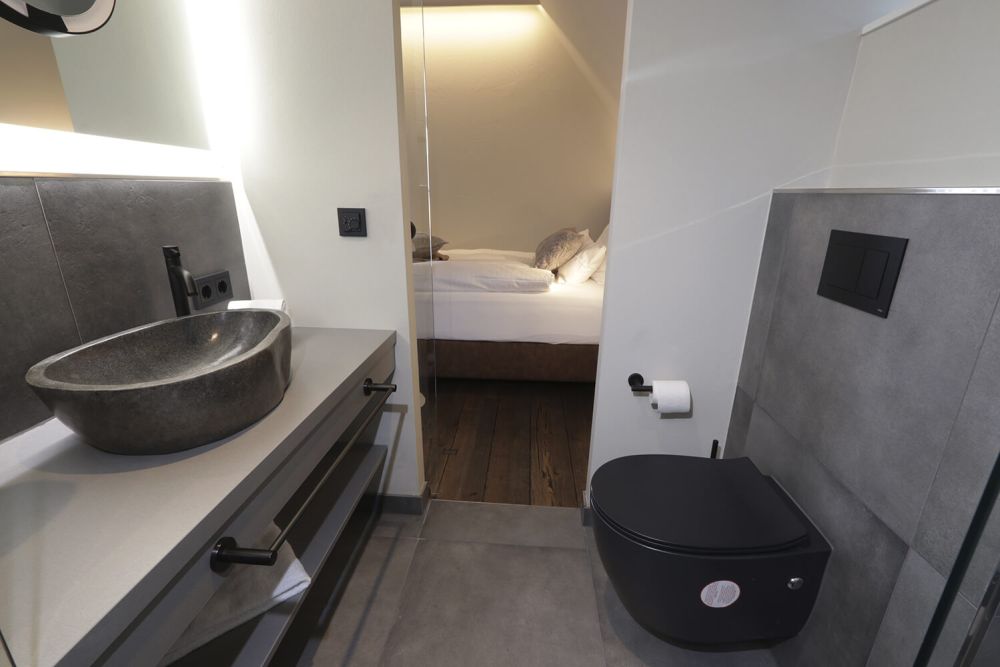 Durch die Schiebetür aus Glas sind Wohnraum und Badezimmer getrennt.