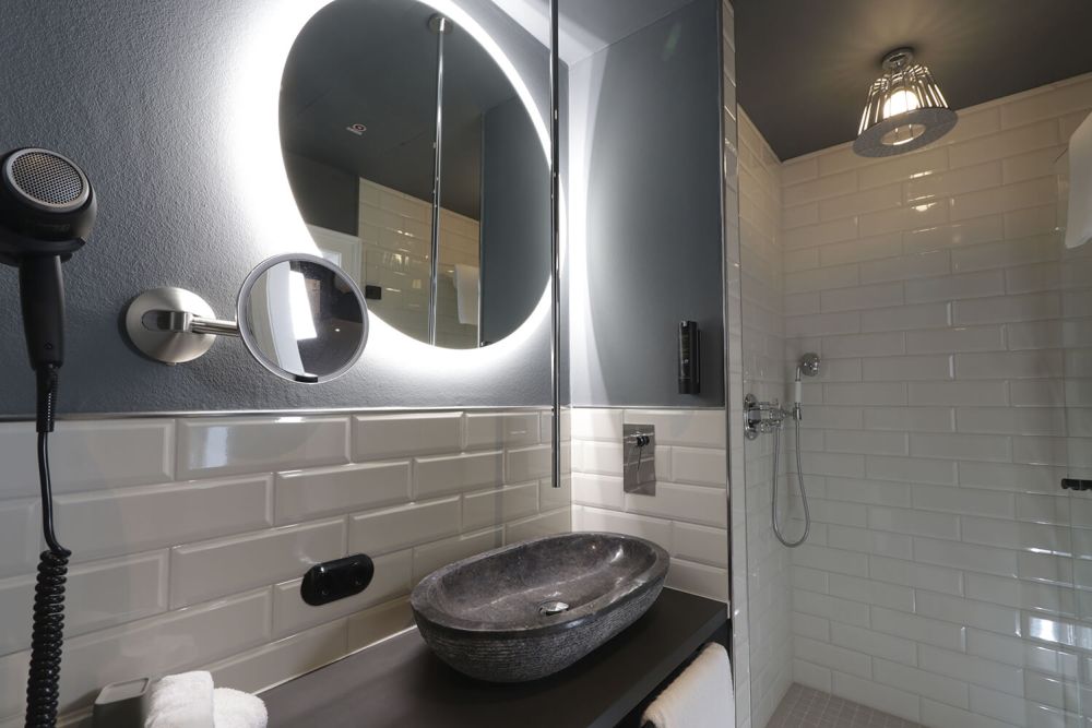 Das Badezimmer mit ebenerdiger Dusche gefliest mit eleganten Metro-Fliesen lässt keine Wünsche offen.