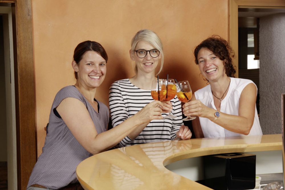 Drei Freundinnen stoßen mit Aperol an