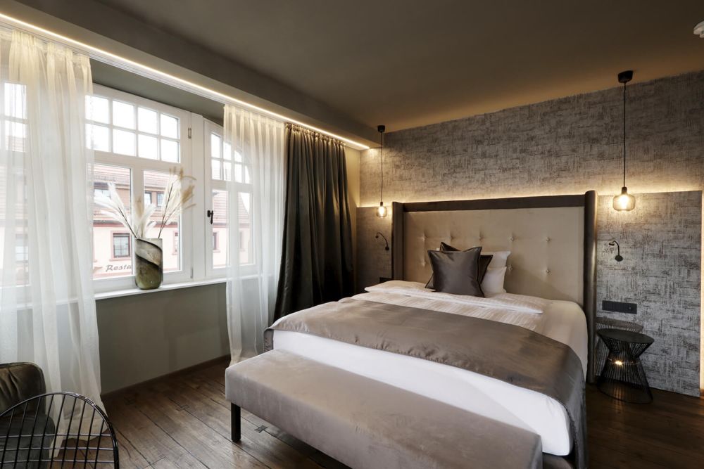 Das gemütliche und einladende Doppelbett steht im Tageslicht-durchflutetem Zimmer.